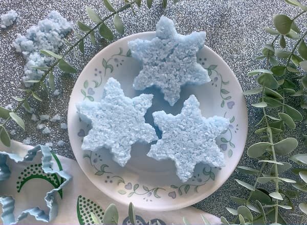 three blue snowflake-shaped bath salt cakes sitting on a plate