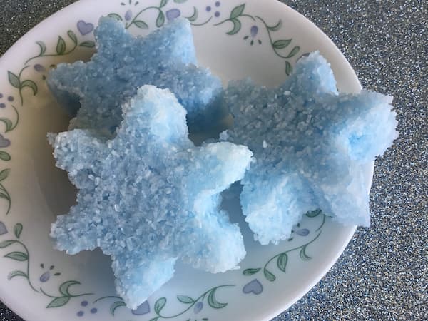 three snowflake-shaped, blue epsom salt cakes sitting on a plate