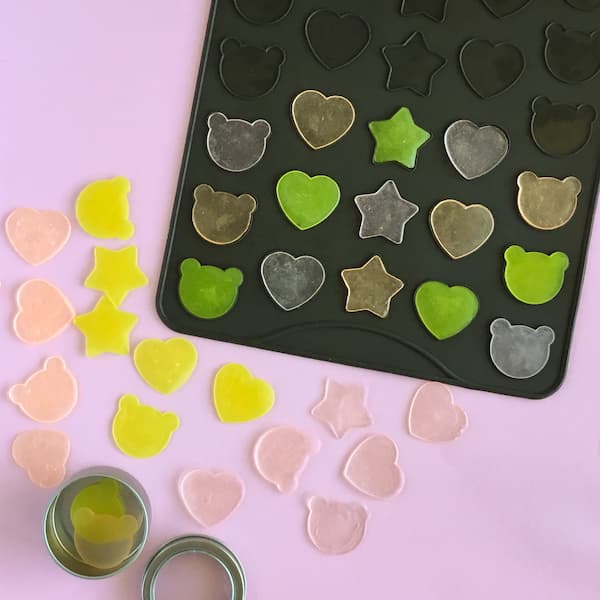 a macaron mat filled with pink, orange, and yellow  melt and pour soap