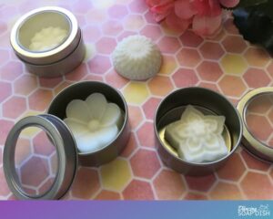floral essential oil lotion bars inside round metal canisters