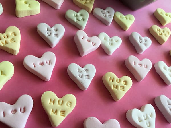 conversation heart style candies laid out on a dark pink background