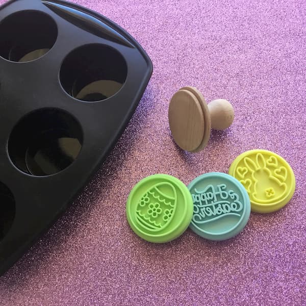 black silicone muffin tray sitting next to three easter-themed cookie stamps