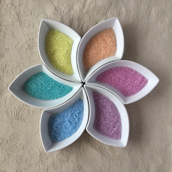 colored epsom salts in six bowls that fit together to make a flower