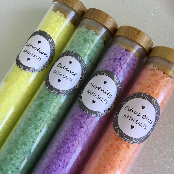 four glass tubes filled with bath salts with round labels displaying the names: doterra elevation, doterra balance, doterra serenity, doterra citrus bliss