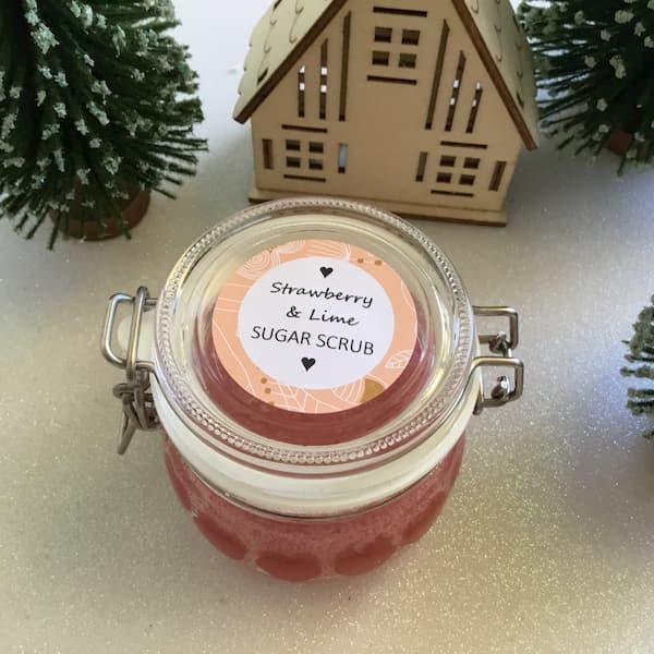 pink colored sugar scrub in an ikea glass jar with a label that reads 'strawberry and lime sugar scrub'