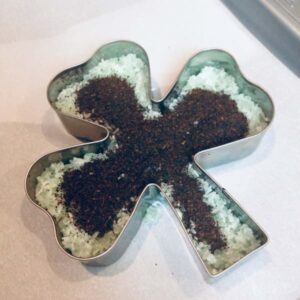 a shamrock-shaped cookie cutter filled with epsom salt and black tea