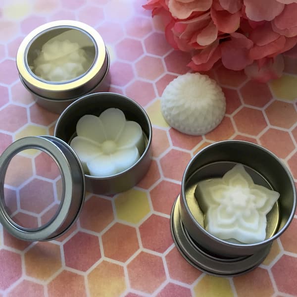 floral essential oil lotion bars inside round metal canisters