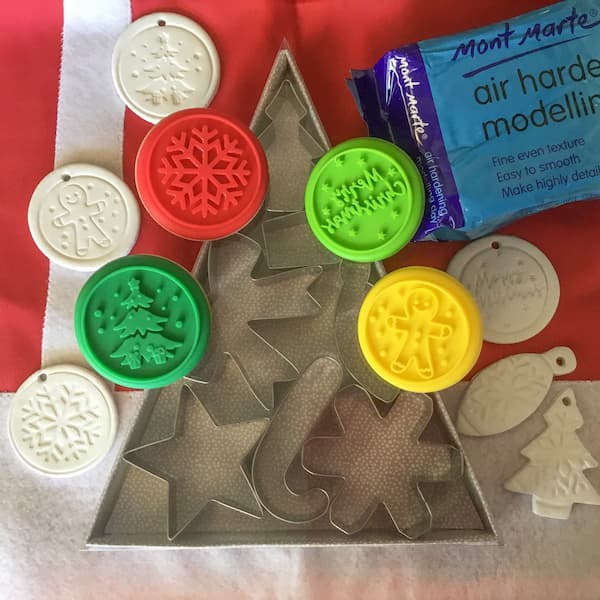christmas cookie cutters and cookie stamps laid out with a packet of white air hardening clay