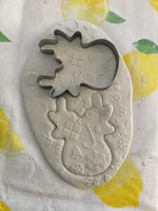 a reindeer shaped cookie cutter pressed into white clay