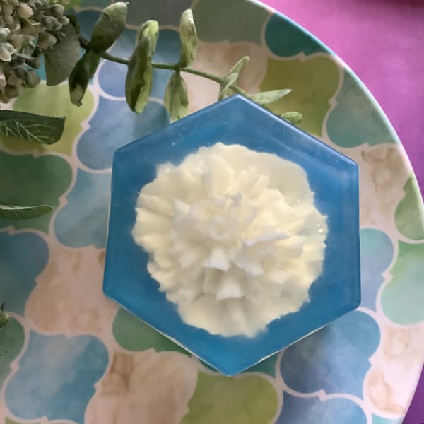 a blue hexagonal soap bar with a white carnation embedded in the centre