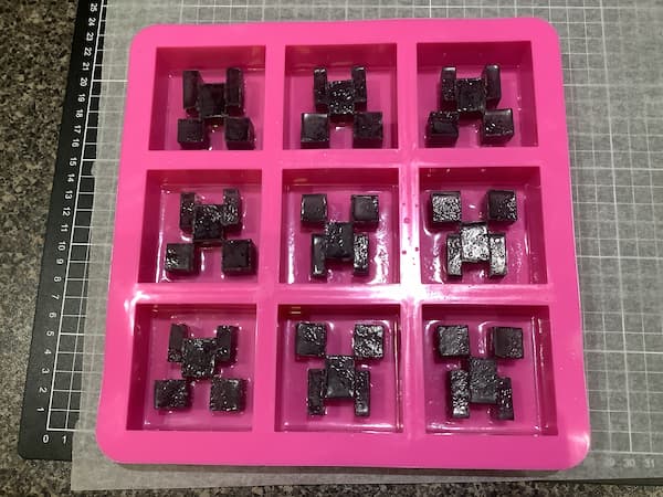 a nine-cavity square mould filled with clear melt and pour soap and minecraft creeper face embeds