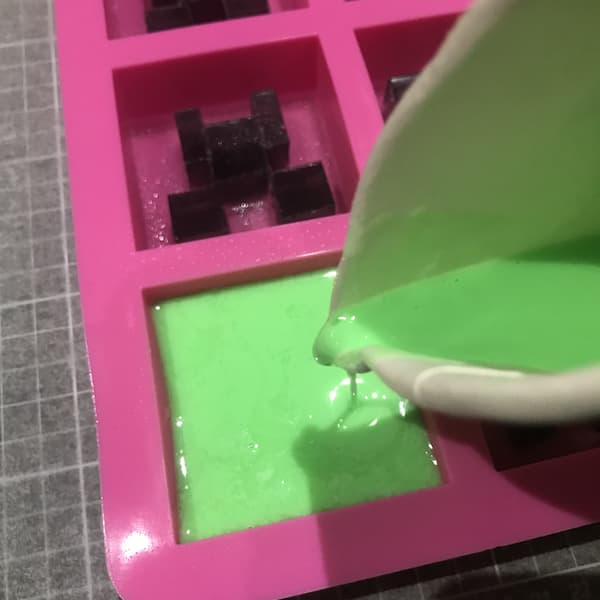pouring green melt and pour soap from a paper cup into a mould