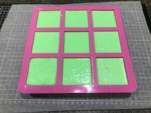 a nine-cavity sqare soap mould filled with green soap