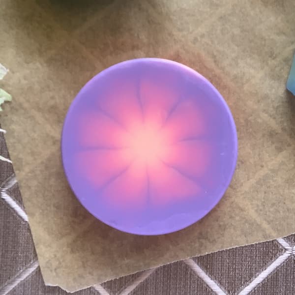 a round soap bar with a purple, pink and orange tie dye effect