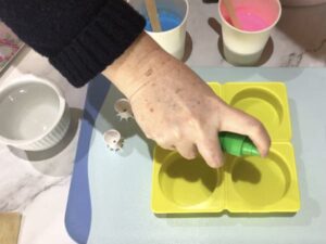 a hand spraying a silicone mould cavity with rubbing alcohol