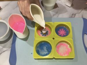 creating a tie dye effect by pouring melted soap base into a paint pouring tool