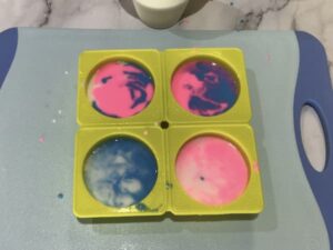 a soap mould filled with swirly pink, blue and white soap base