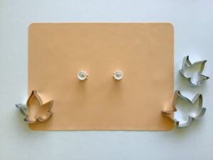 a peach coloured silicone baking mat, three leaf shaped cookie cutters and two acrylic paint pouring funnels