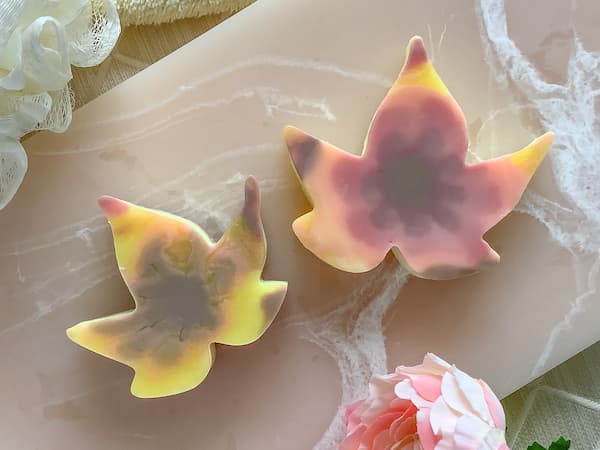 two autumn leaf soap bars sitting on a pink resin board