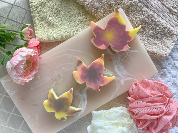 autumn leaf melt and pour soap bars on a pink resin board surrounded by face washers and loofas