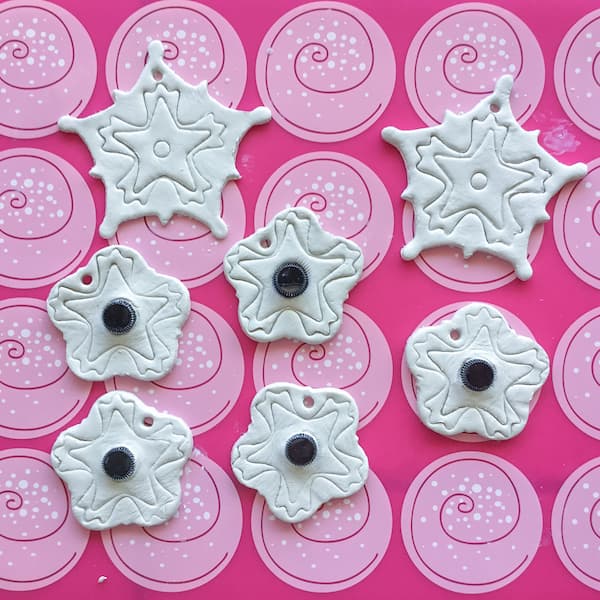 snowflake and sample bottle embedded diffuser ornaments laid out on a pink silicone baking mat