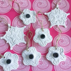 snowflake and sample bottle embedded diffuser ornaments laid out on a pink silicone baking mat