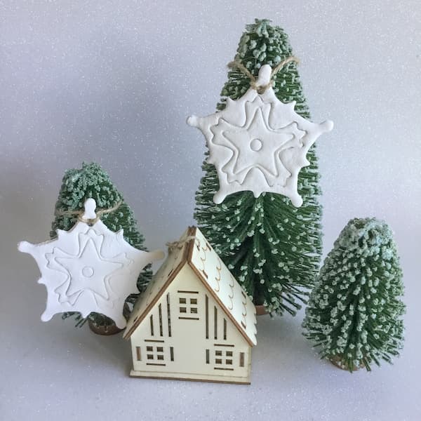 white clay embossed snowflake essential oil diffuser ornaments hanging on a ornamental pine tree