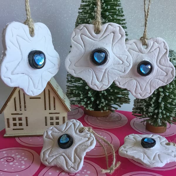 five white clay diffuser ornaments with essential oil vials embedded in the centre. each black vial cap has a blue heart gem stuck to it.