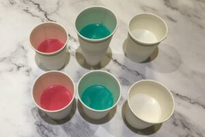 six paper cups with red, green and white melt and pour soap inside