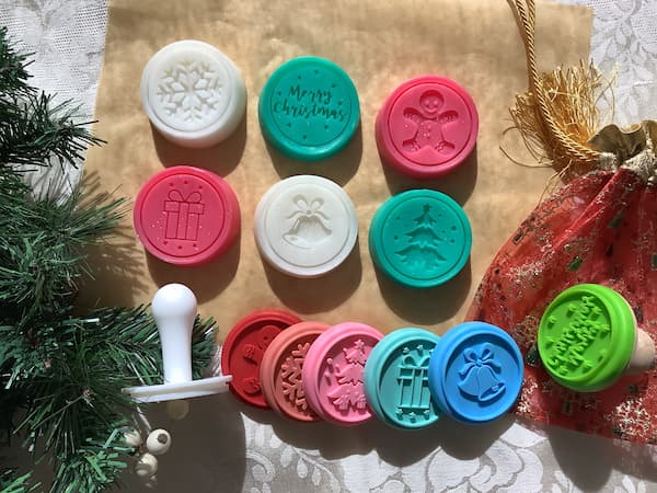 six Christmas themed cookie stamp soap bars laid out with six silicone cookie stamps