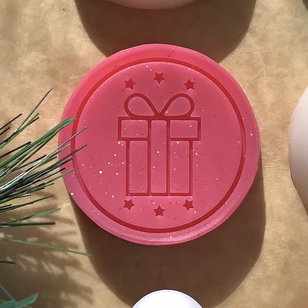 round red bar of soap with a picture of a Christmas gift embossed on the front