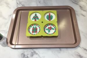 four round soap bars with Christmas themed mosaic tile designs sitting on top of them