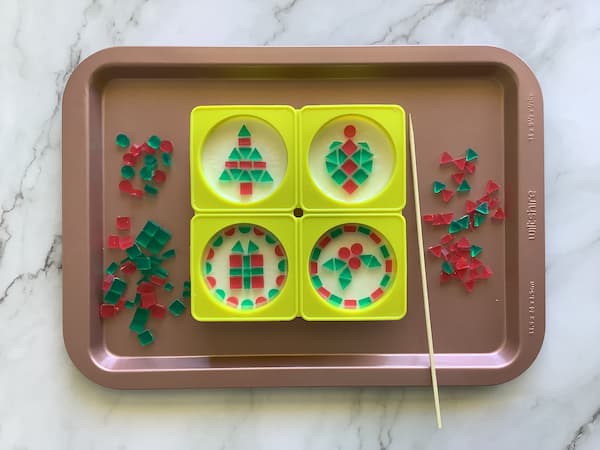 four mosaic Christmas soaps sitting on a tray surrounded by red and green mosaic tiles
