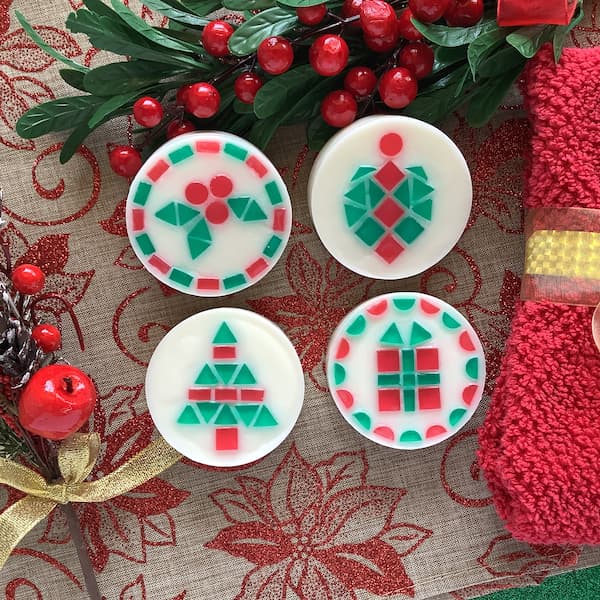 four Christmas themed mosaic soap bars displaying holly, ornament, Christmas tree, and Christmas gift designs