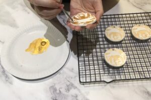a hand painting another coat of gold paint on a clay ornament
