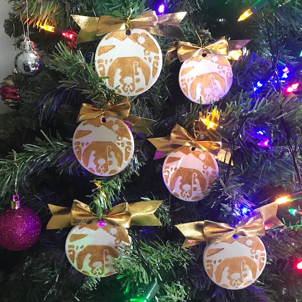 six stamped nativity ornaments hanging on a tree