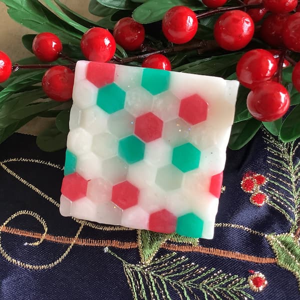 a square bar of soap covered in white, green, red and glitter hexagonal mosaic tiles