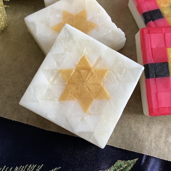 a square bar of soap with an image of a Christmas star laid out in white and gold, triangle-shaped mosaic tiles