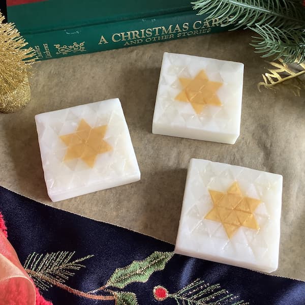 three square bars of soap with an image of a Christmas star laid out in white and gold, triangle-shaped mosaic tiles