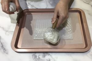 white, pearlescent soap being poured into a mosaic silicone mould