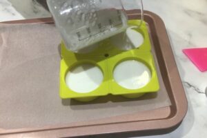 filling a four cavity round soap mould with white soap base