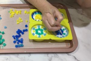 using a bamboo skewer to position mosaic soap tiles in a round mould
