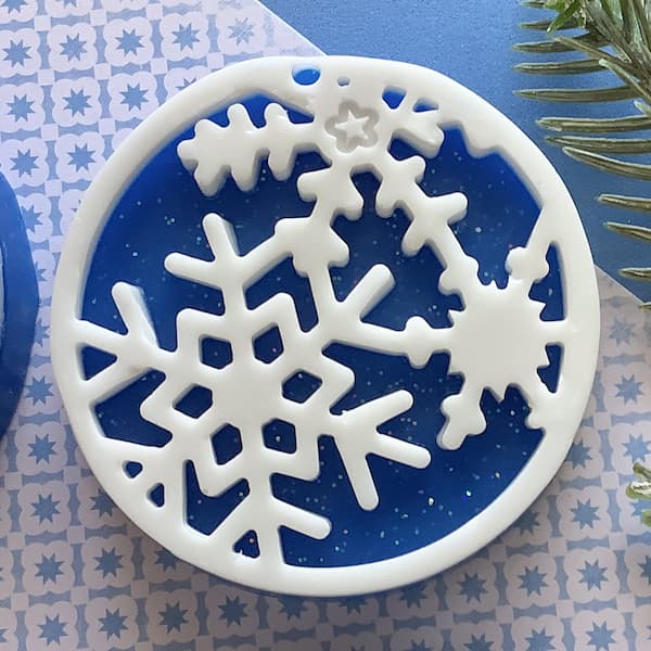 a dark blue round bar of soap with a white snowflake silhouette on top