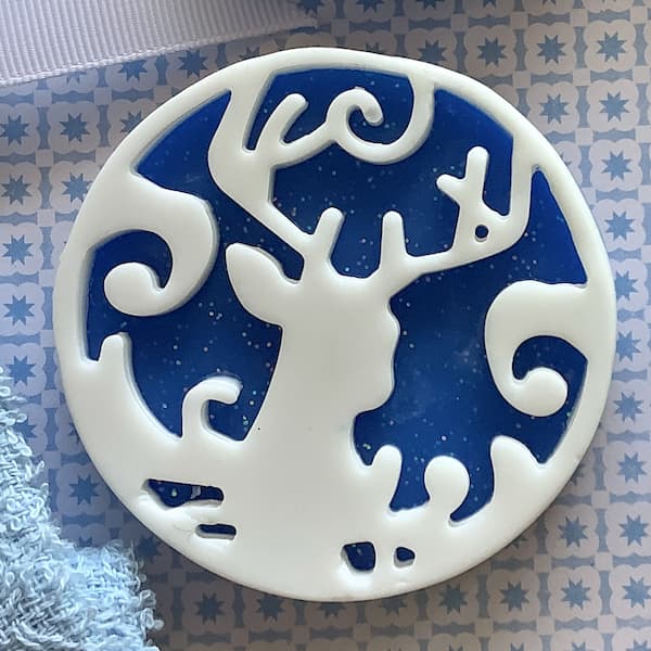 a dark blue round bar of soap with a white reindeer head silhouette on top
