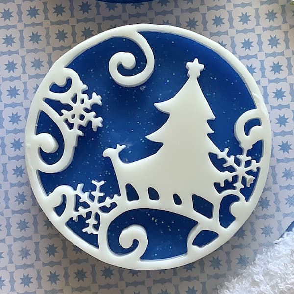 a dark blue round bar of soap with a white snow scene silhouette on top