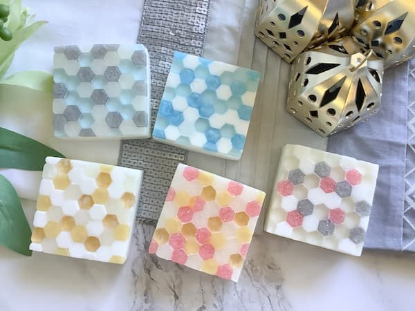 five glass tile effect soap bars laid out on a white marble background