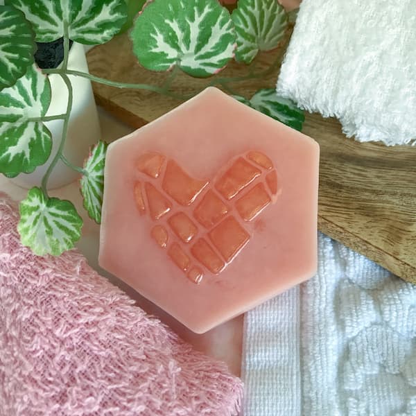 a hexagonal-shaped soap bar with a rose gold coloured mosaic heart in the centre