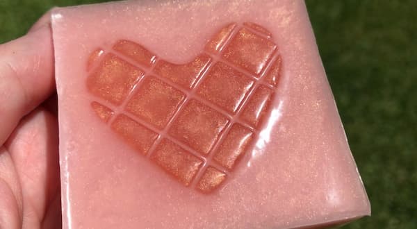 a square rose gold coloured soap bar with a mosaic tile heart in the centre glistening in the sun
