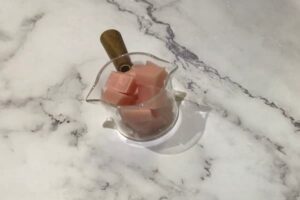 a small glass measuring cup filled with rose gold soap cubes