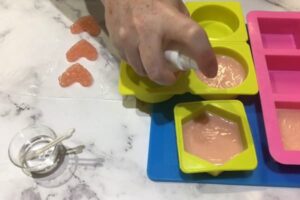a hand spraying the surface of a soap bar with alcohol
